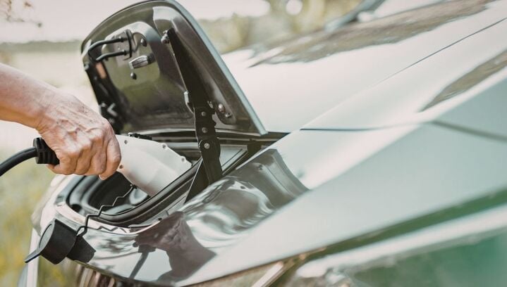 An electric vehicle being plugged in by the owner.